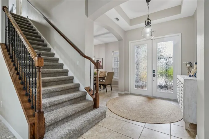 Foyer featuring light tile patterned floors, a raised ceiling, and french doors
