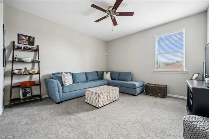 Carpeted living room featuring ceiling fan