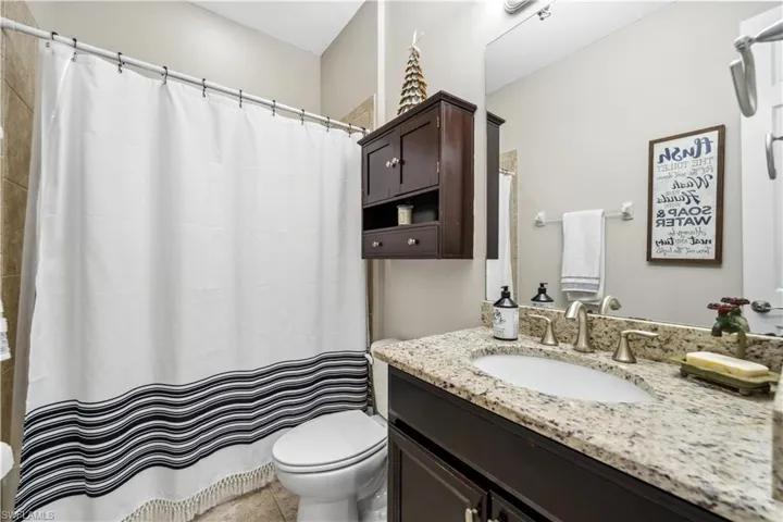 Bathroom featuring tile patterned floors, toilet, curtained shower, and vanity