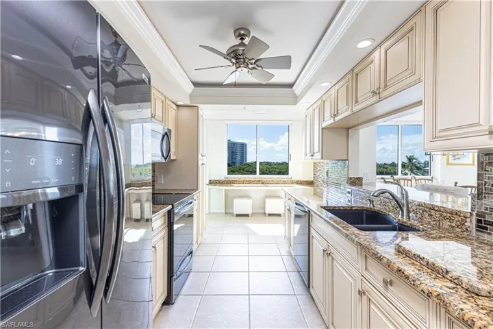Kitchen featuring a wealth of natural light, stainless steel appliances, light stone counters, and ceiling fan