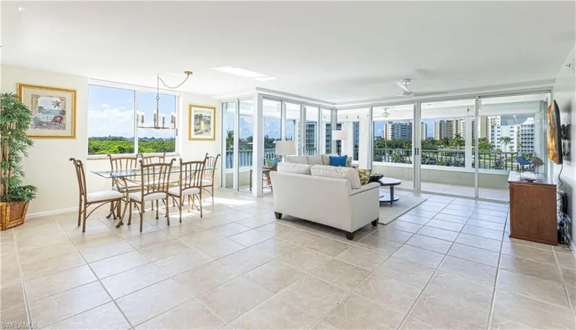 Tiled living room with plenty of natural light, ceiling fan, and floor to ceiling windows