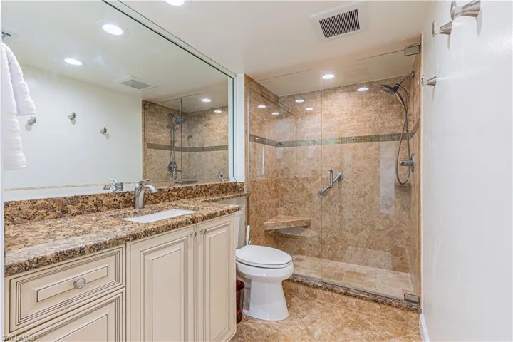 Second bathroom with a shower, glass door, vanity, and toilet