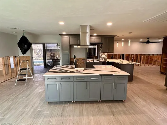 Kitchen featuring hanging light fixtures, a kitchen island, and gray cabinetry