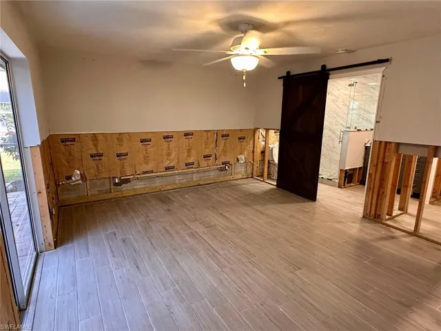 Unfurnished room featuring light hardwood / wood-style floors, a barn door, and ceiling fan