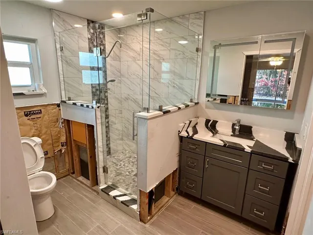 Bathroom with vanity, a shower with door, and toilet