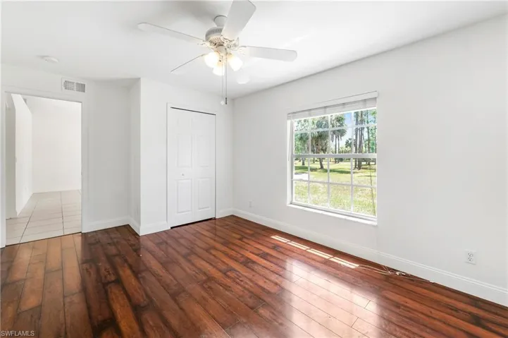 Room featuring wood-finish flooring, white walls, and a multi-pane window with exterior scenery