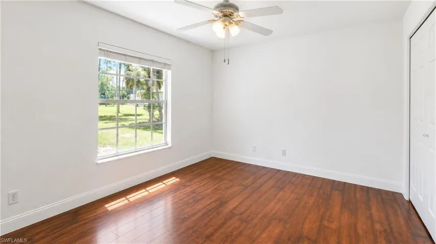 Bedroom featuring wood-finish flooring, white walls, and a multi-pane window with white blinds
