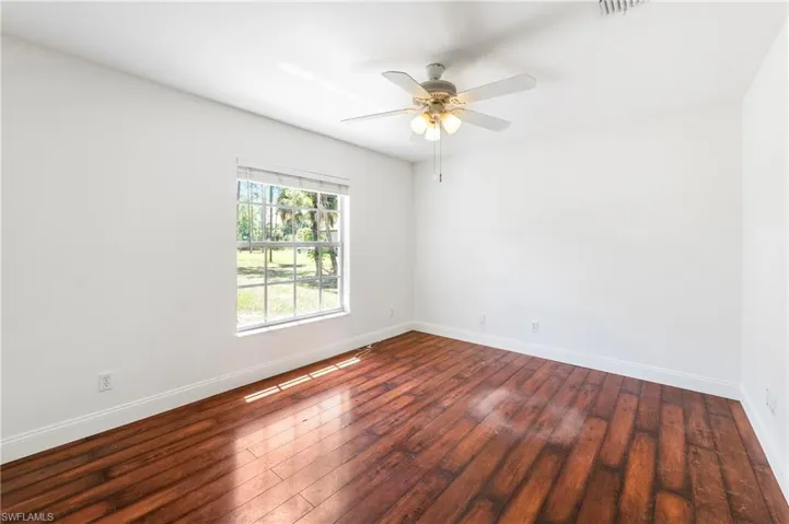 Room featuring wood-finish flooring, white walls, and a ceiling fan with integrated lighting