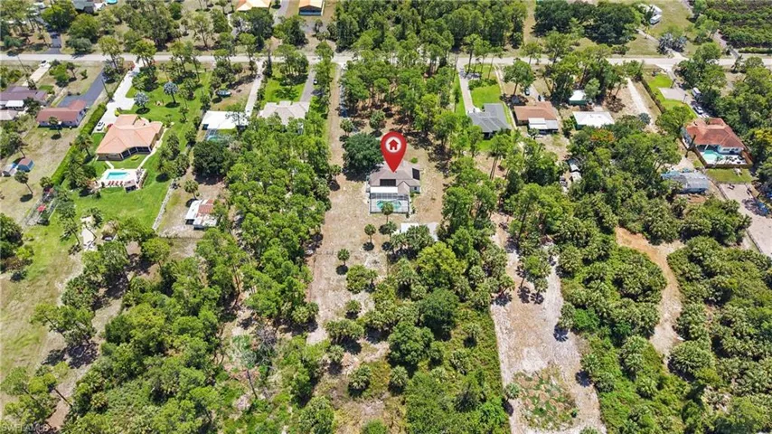 Paved driveway surrounded by mature palm trees and lush green lawn, offering a secluded setting