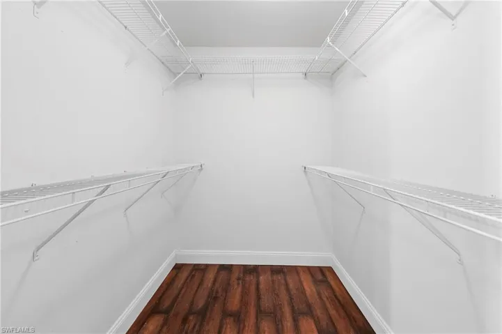 Walk-in closet featuring white wire shelving, white walls, white trim, and wood-finish flooring