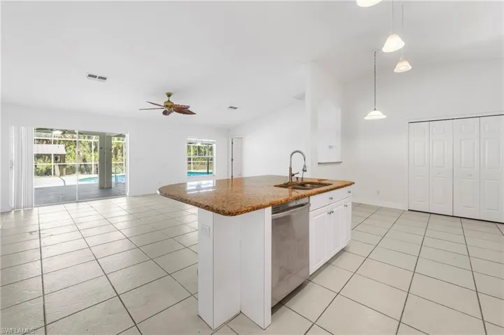 Kitchen island with a light granite countertop, undermount stainless steel sink, and stainless steel dishwasher