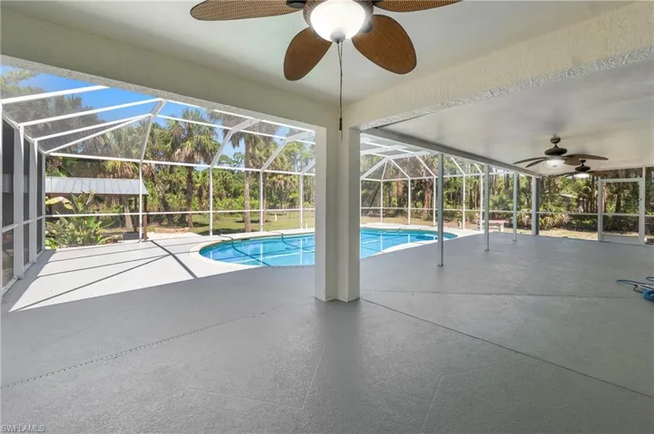 Expansive screened enclosure featuring a swimming pool and textured concrete flooring