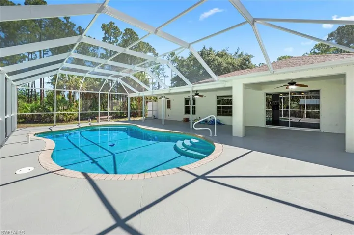 Screened outdoor pool area featuring a freeform pool with integrated steps, a paver coping, and a spacious deck