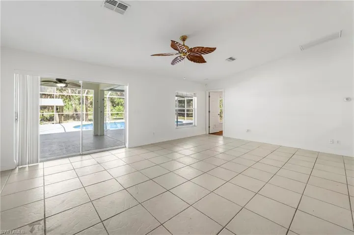 Spacious interior featuring light-toned tile flooring, a decorative ceiling fan, and white walls