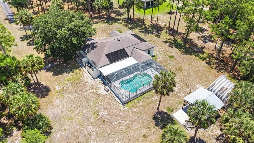 Residence with a screened-in pool, a covered patio, and solar panels on the roof