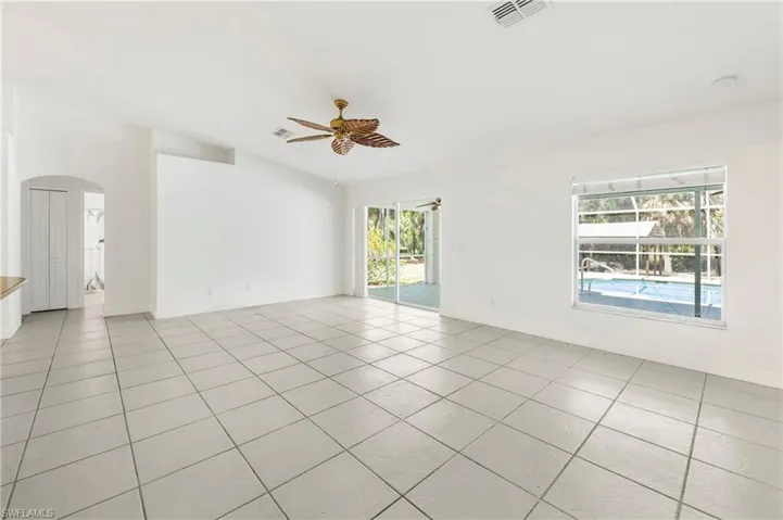 Spacious interior featuring neutral tile flooring, vaulted ceilings, and a decorative ceiling fan
