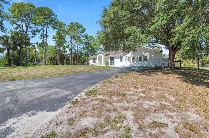 Expansive paved driveway leading to a white exterior residence