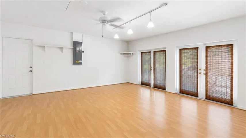Spacious room featuring wood-finish flooring, a ceiling fan, track lighting, and multiple sets of glass-paned doors