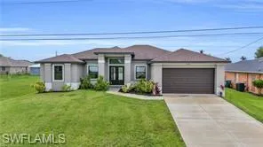 View of front of home featuring driveway, a front lawn, and a garage