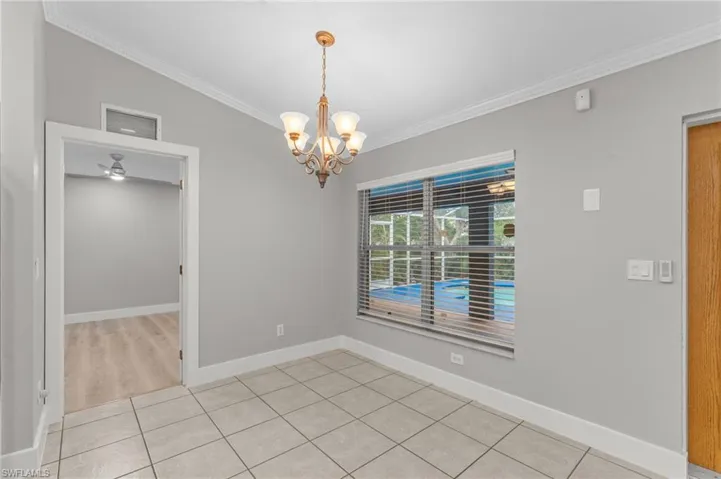 Unfurnished dining area featuring light tile patterned floors, suspended lighting, crown molding, a ceiling fan, and lofted ceiling