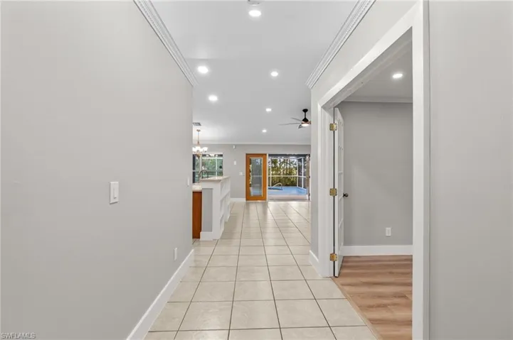 Hall featuring light tile patterned floors, crown molding, and recessed lighting