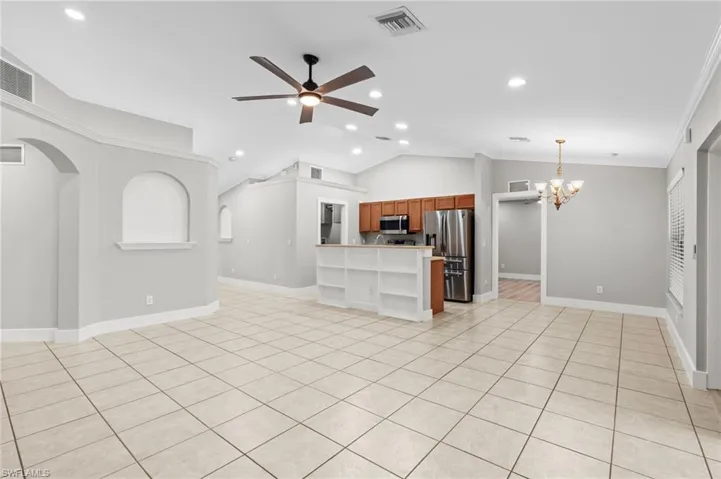 Kitchen featuring wood finish cabinetry, open floor plan, ceiling fan, stainless steel appliances, and ornamental molding