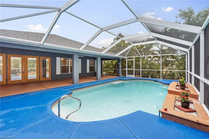 Swimming pool with a lanai, a sunroom, a patio area, and french doors