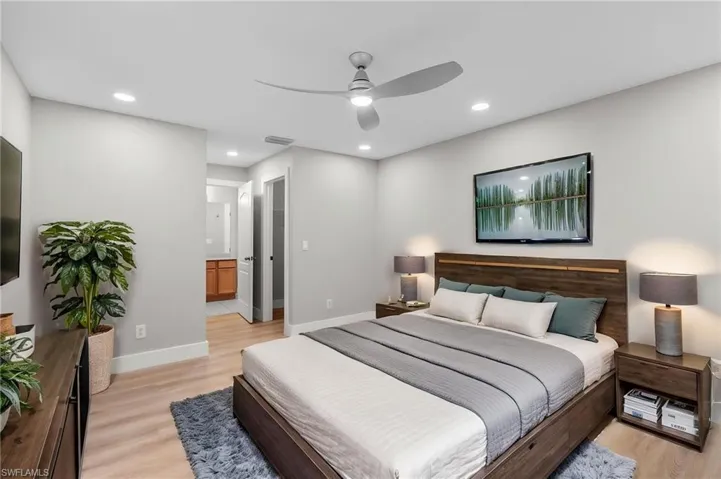 Bedroom with light wood-style flooring, a ceiling fan, ensuite bathroom, and recessed lighting