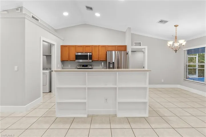Kitchen featuring open shelves, wood finish cabinets, light countertops, a chandelier, and lofted ceiling