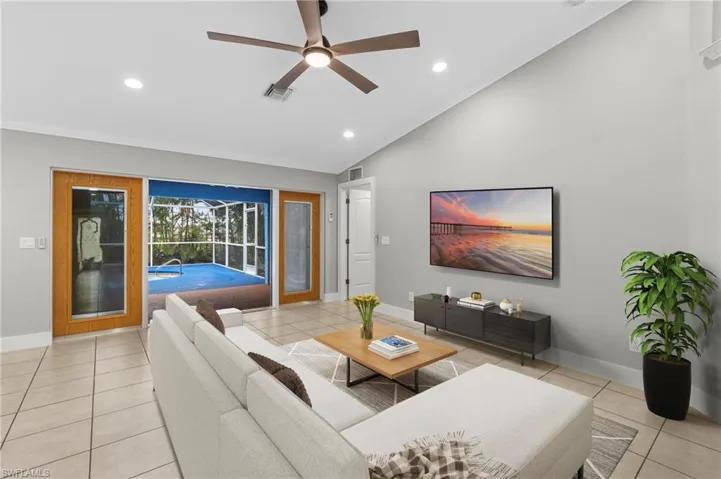 Living area with a sunroom, lofted ceiling, a ceiling fan, light tile patterned floors, and recessed lighting