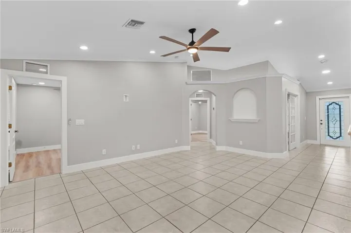 Empty room featuring arched walkways, a ceiling fan, recessed lighting, vaulted ceiling, and light tile patterned floors