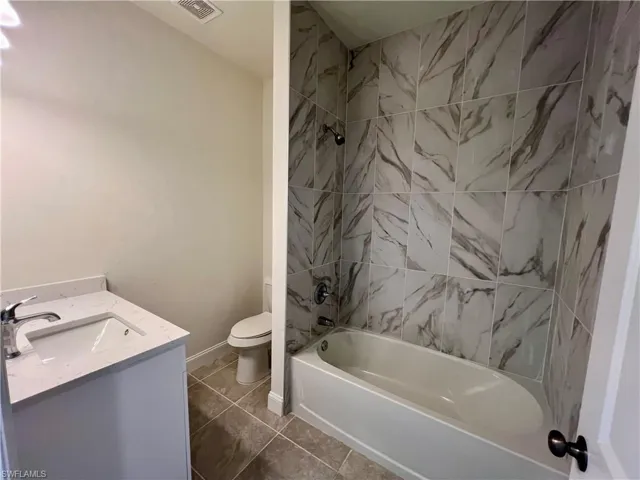 Full bathroom featuring tile patterned floors, vanity, toilet, and tiled shower / bath combo