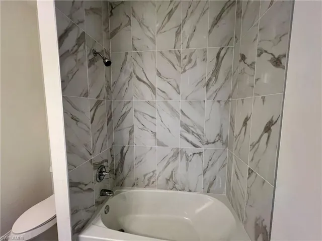 Bathroom with toilet and tiled shower / bath