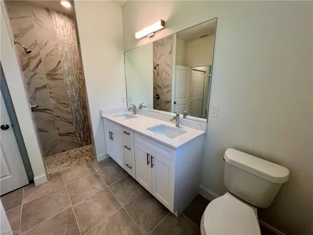 Primary bathroom with dual sinks, QUARTZ TOPS and a tiled walk in shower.