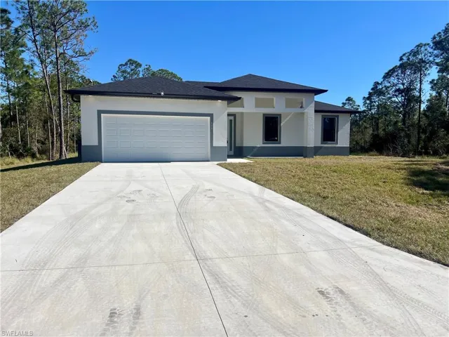 Front of home featuring a front yard, garage and extra long driveway for plenty of cars.