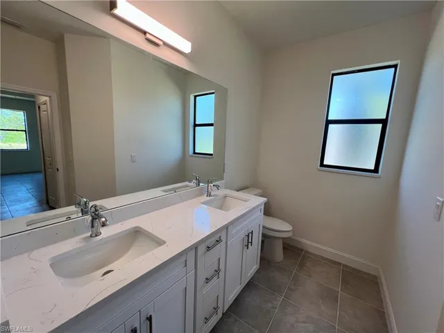 Primary bathroom with dual sinks, QUARTZ TOPS and a tiled walk in shower.