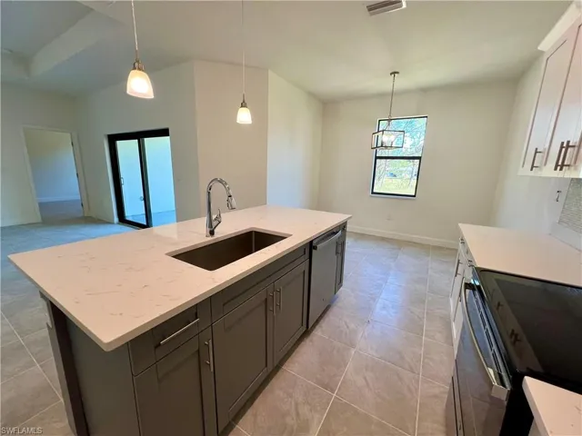 Kitchen featuring a kitchen island with sink, hanging light fixtures, sink, stainless steel dishwasher, and QUARTZ TOPS.