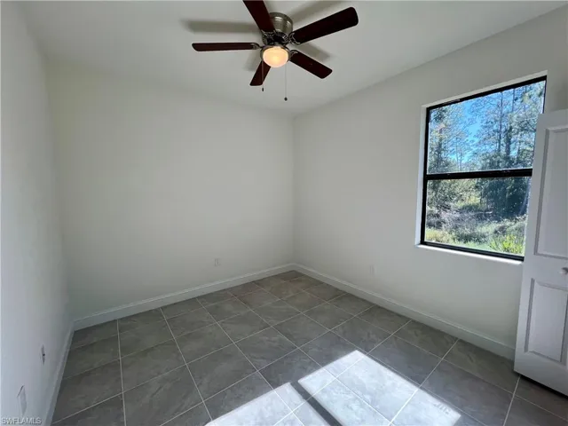 Tiled bedroom with ceiling fan and a healthy amount of sunlight