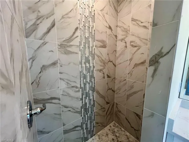 Primary bathroom with tiled walk in shower with glass tile accents.