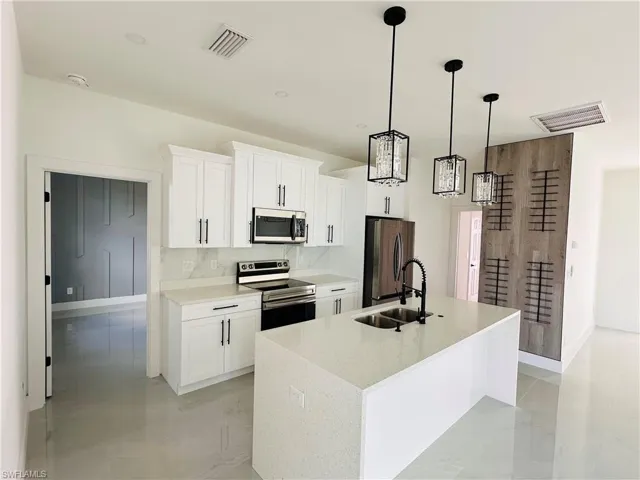 Kitchen with visible vents, white cabinets, an island with sink, appliances with stainless steel finishes, and a sink