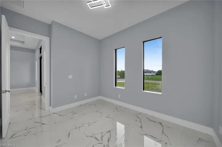 Unfurnished room featuring baseboards and light marble finish flooring