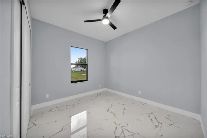 Spare room featuring marble finish floors, a smoke detector, and ceiling fan