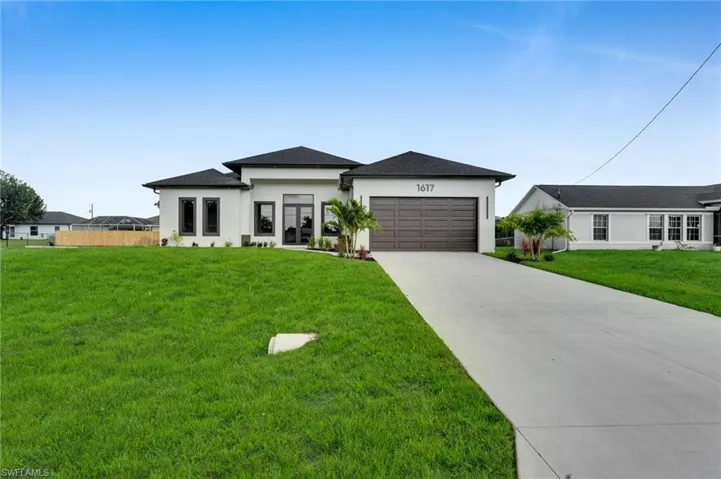Prairie-style house featuring stucco siding, an attached garage, driveway, and a front yard