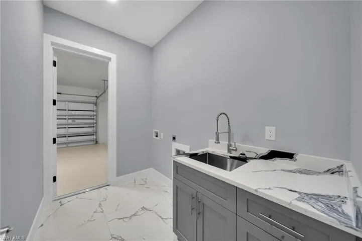 Washroom featuring electric dryer hookup, light marble finish flooring, cabinet space, and hookup for a washing machine