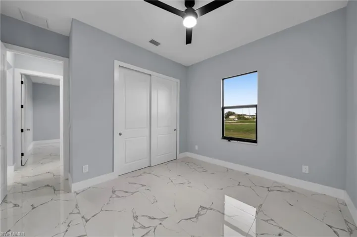 Unfurnished bedroom with marble finish flooring, a closet, and a ceiling fan