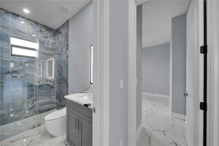 Bathroom with marble tiled flooring, a marble finish shower, vanity, and recessed lighting