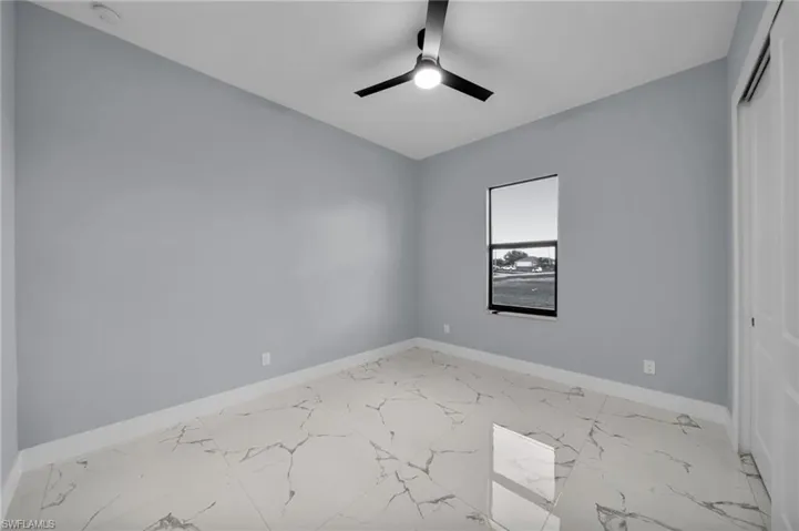 Unfurnished room featuring light marble finish floors, ceiling fan, and a smoke detector