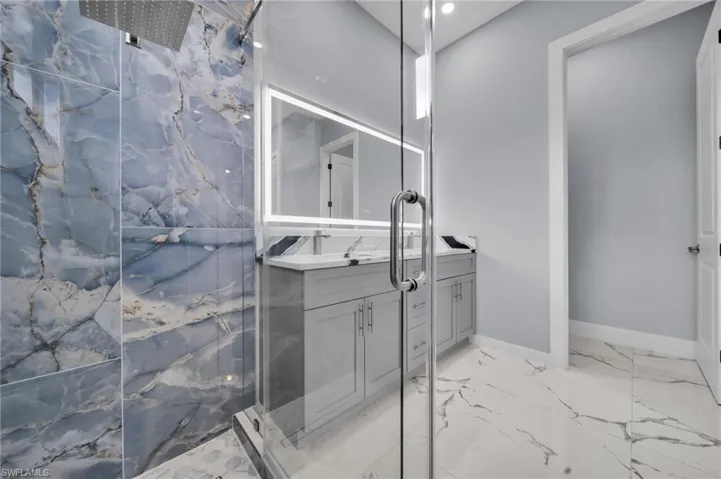 Bathroom featuring vanity, a marble finish shower, marble finish floors, and recessed lighting