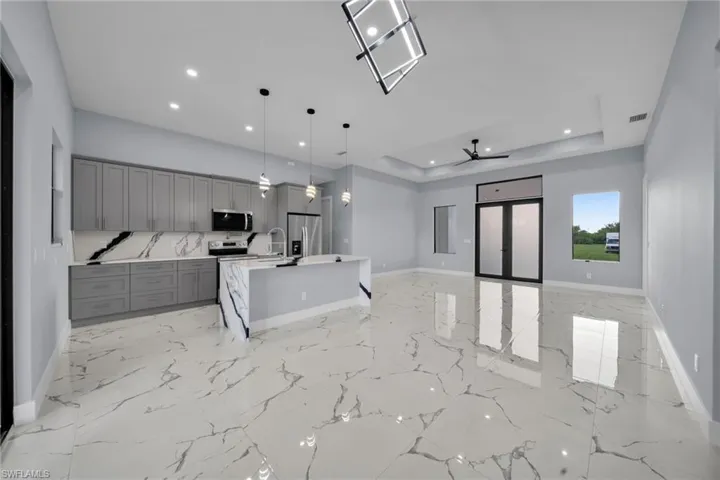Kitchen featuring stainless steel appliances, gray cabinets, open floor plan, recessed lighting, and light countertops