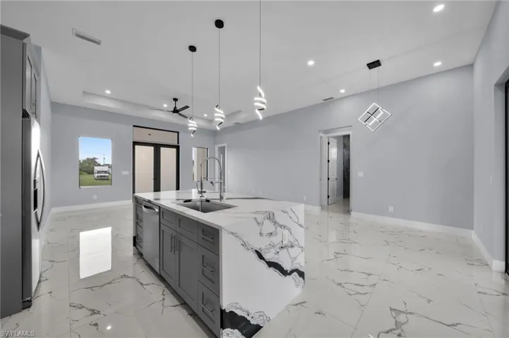 Kitchen with appliances with stainless steel finishes, gray cabinets, recessed lighting, open floor plan, and light stone countertops